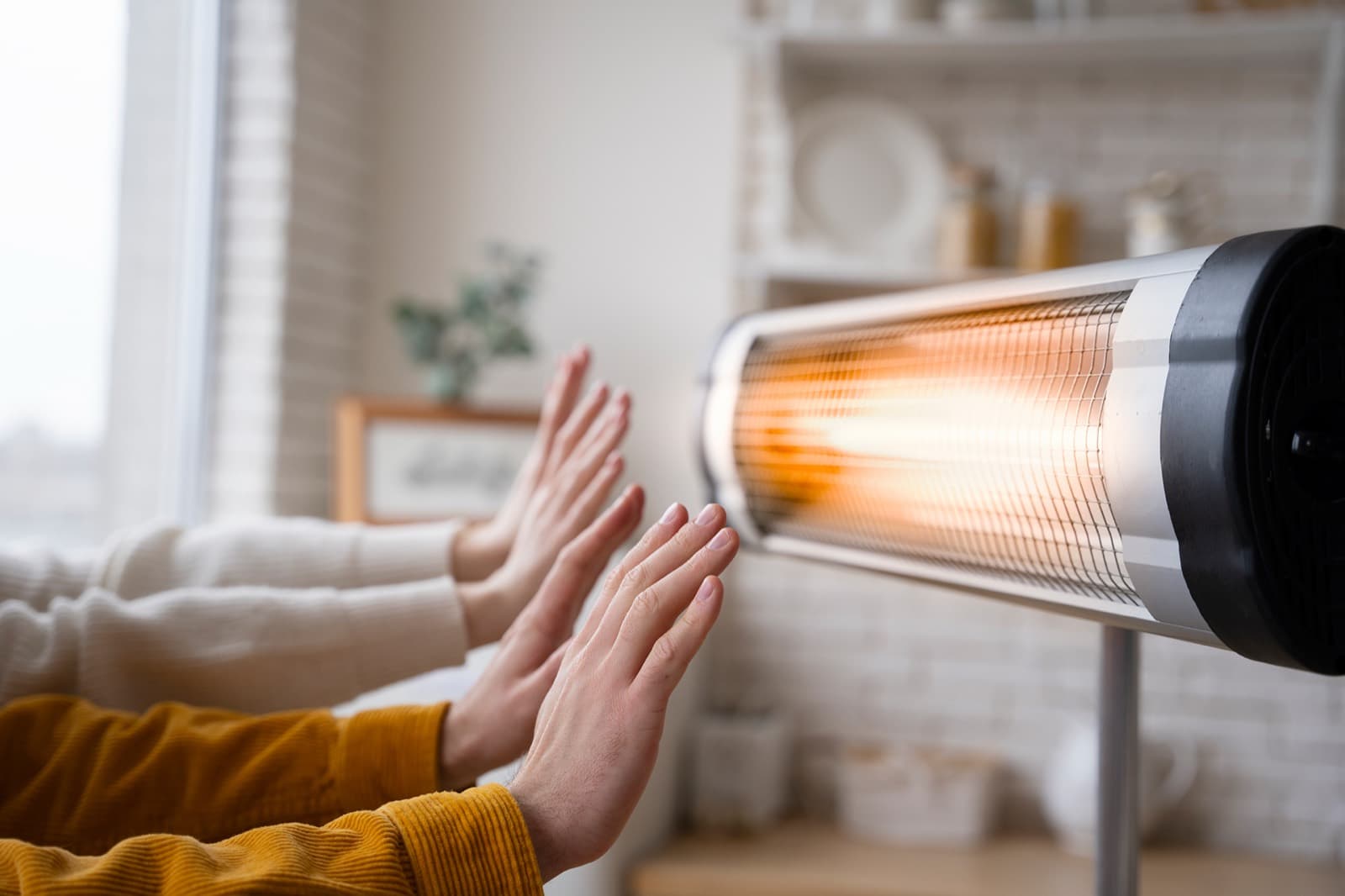 Mains qui se réchauffent devant un appareil de chauffage